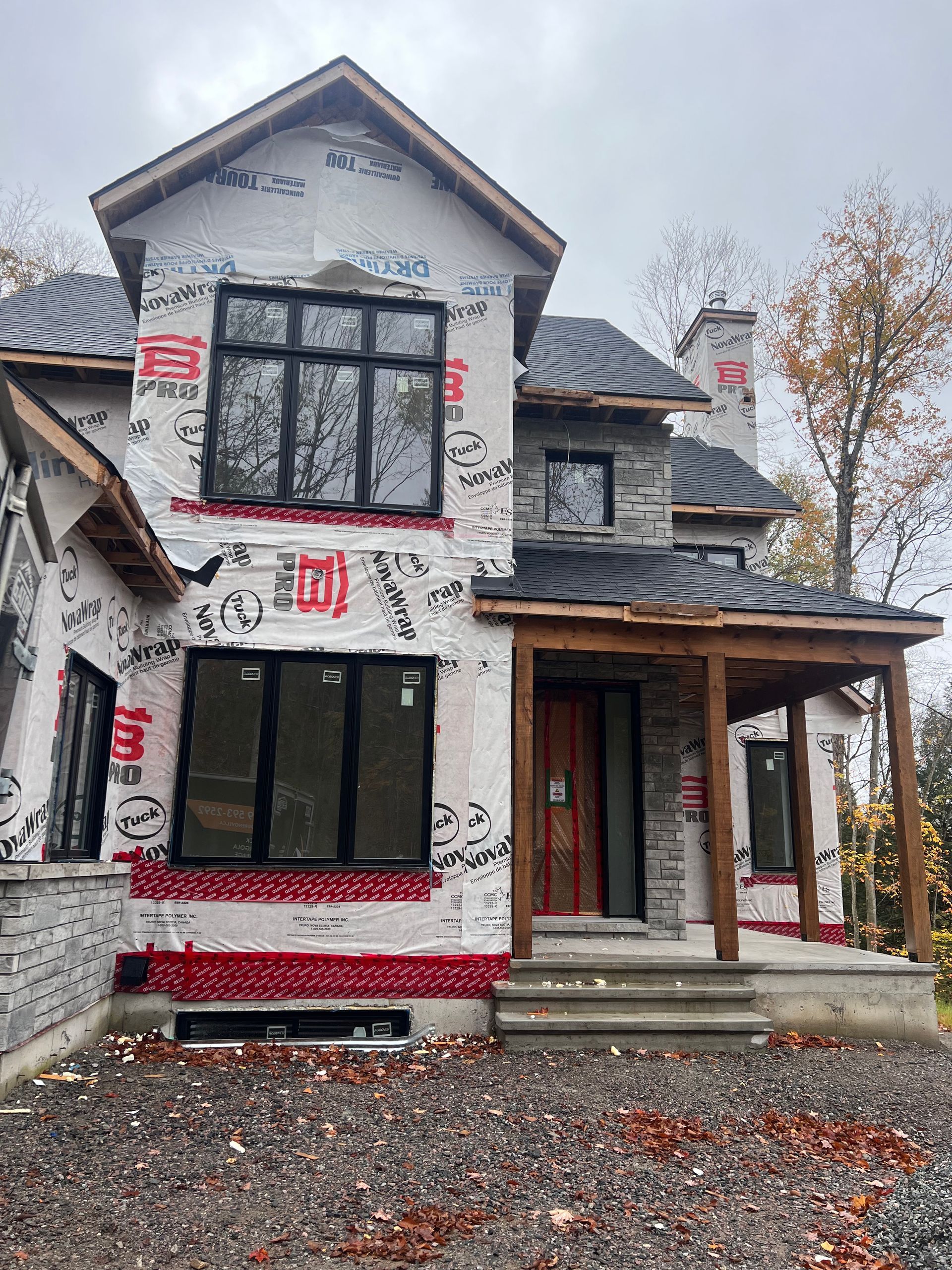 Maison à deux étages partiellement rénovée avec isolation apparente et porche avant dans un quartier verdoyant