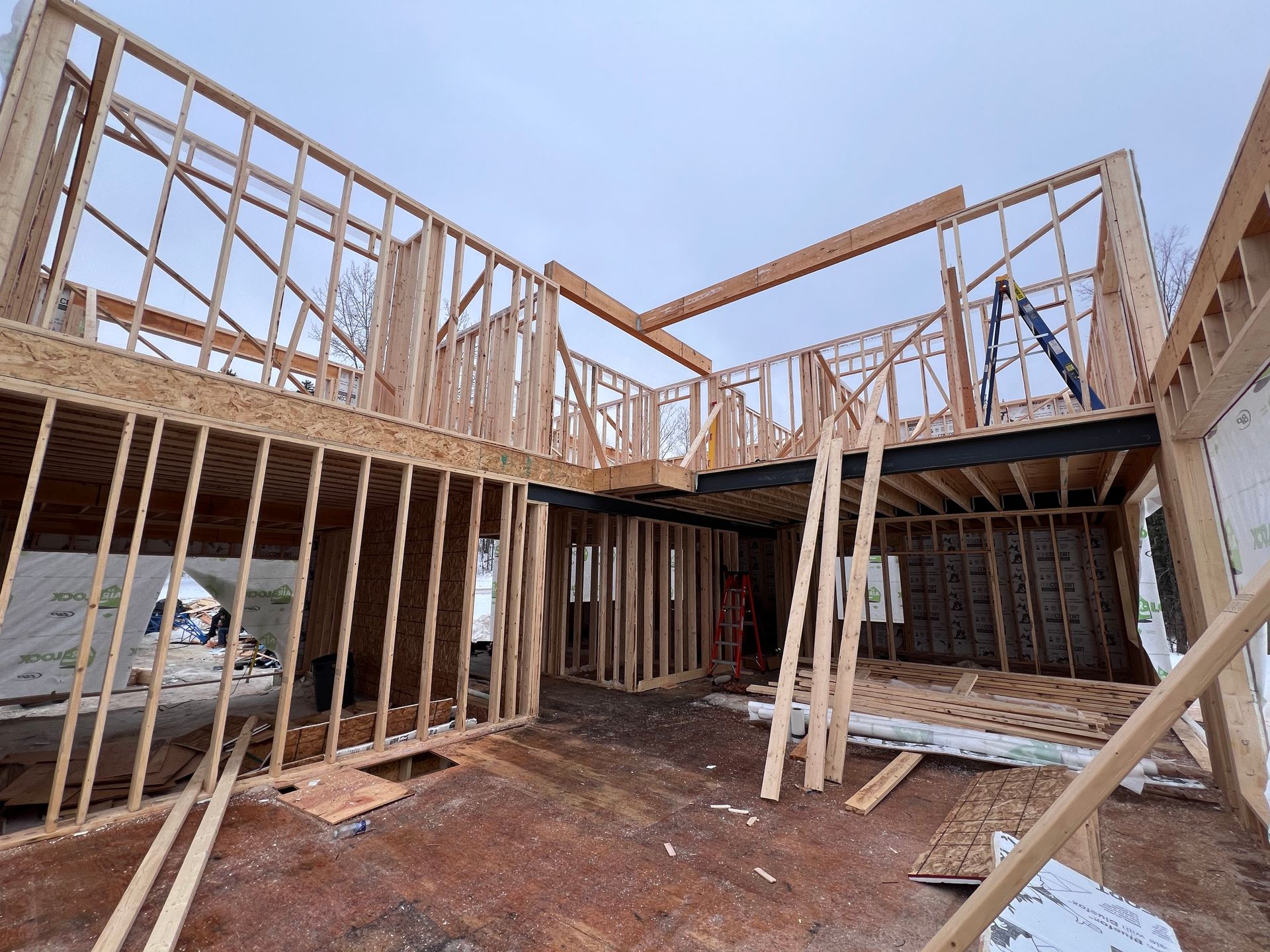 Maison à ossature bois en construction avec fermes apparentes et poutres de soutien temporaires