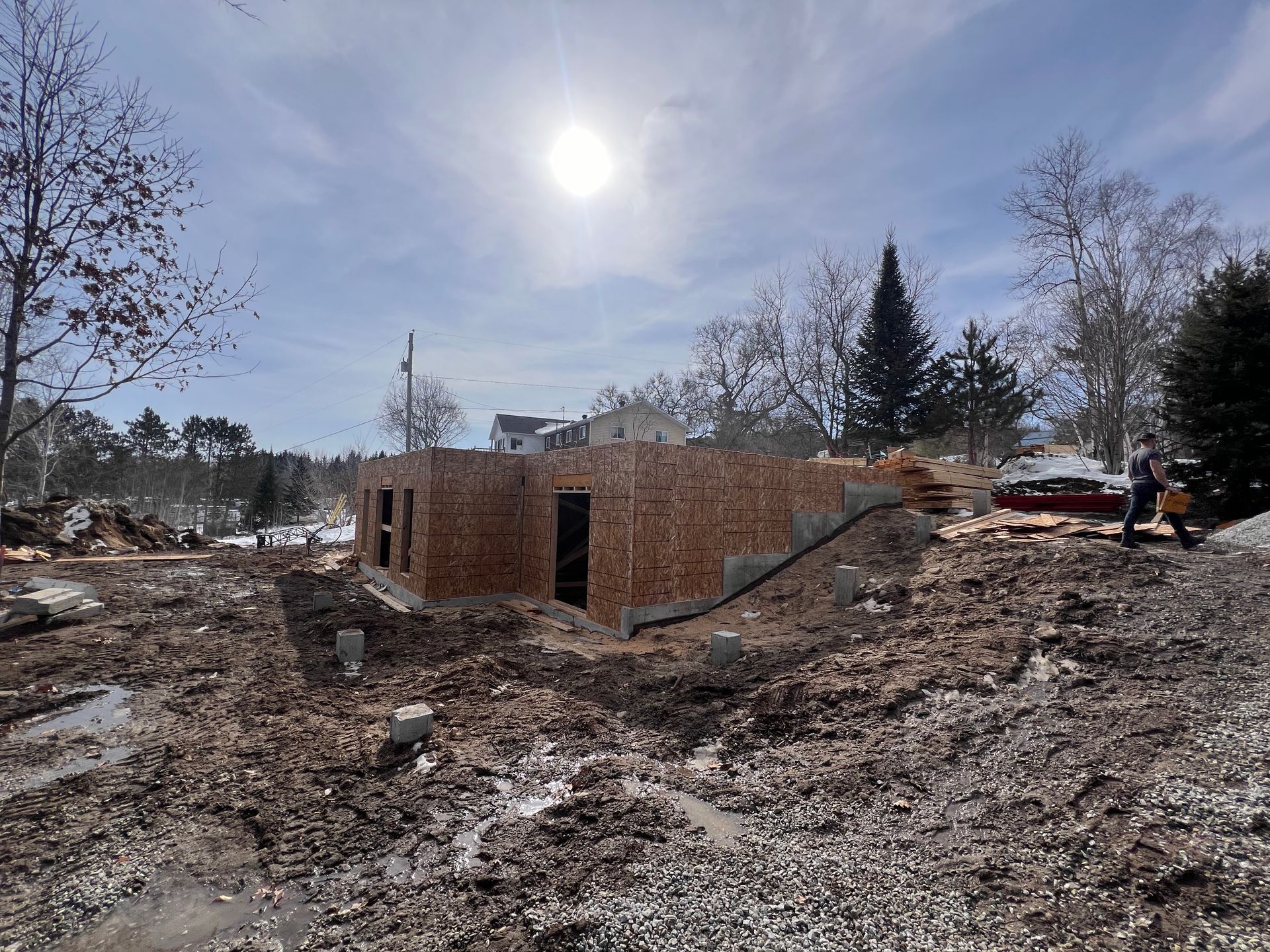 Structure en briques partiellement construite sur un terrain dégagé sous un soleil éclatant, avec des débris de construction au premier plan.