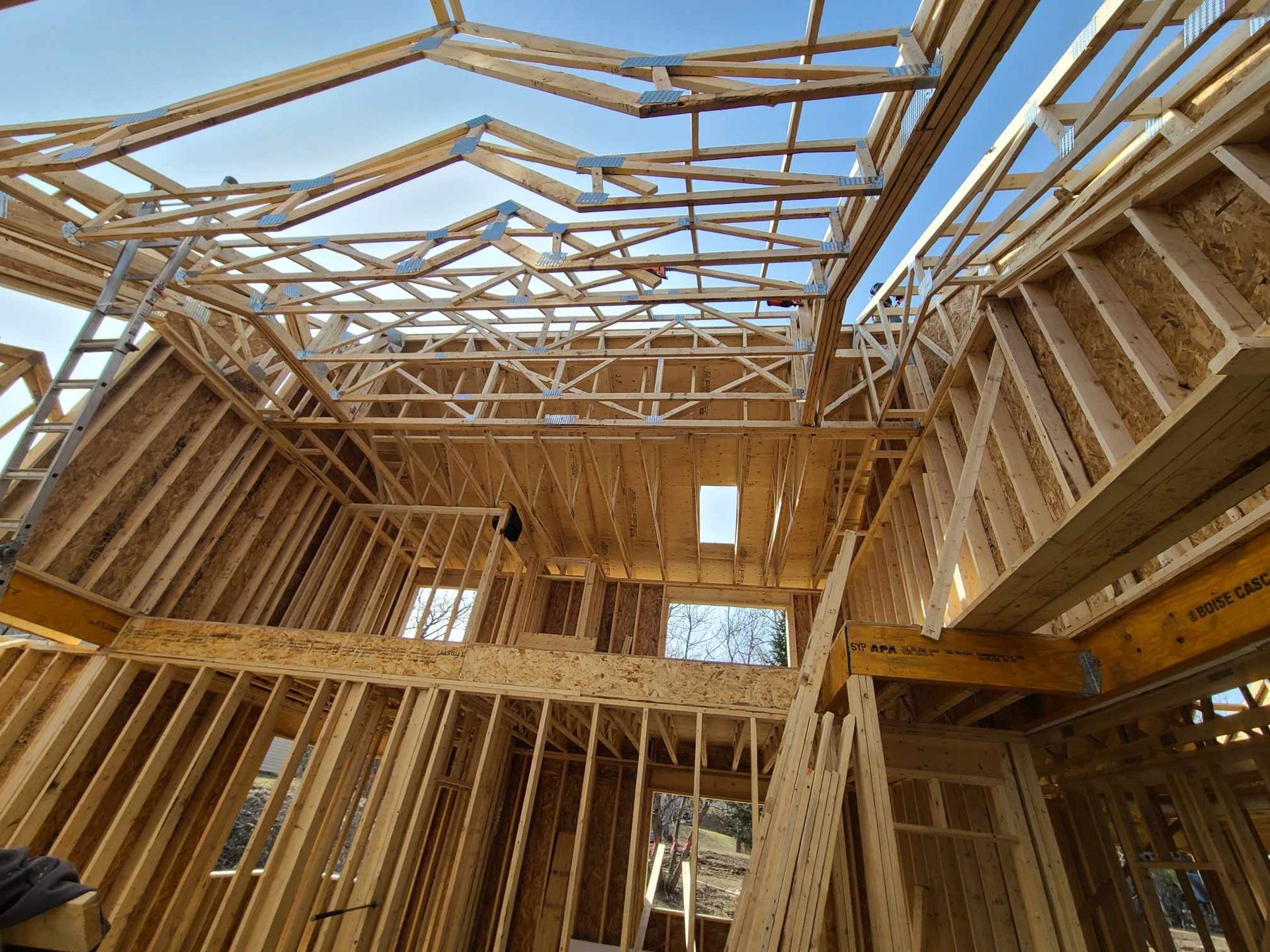 Maison à ossature bois en construction avec charpente apparente et murs intérieurs ouverts