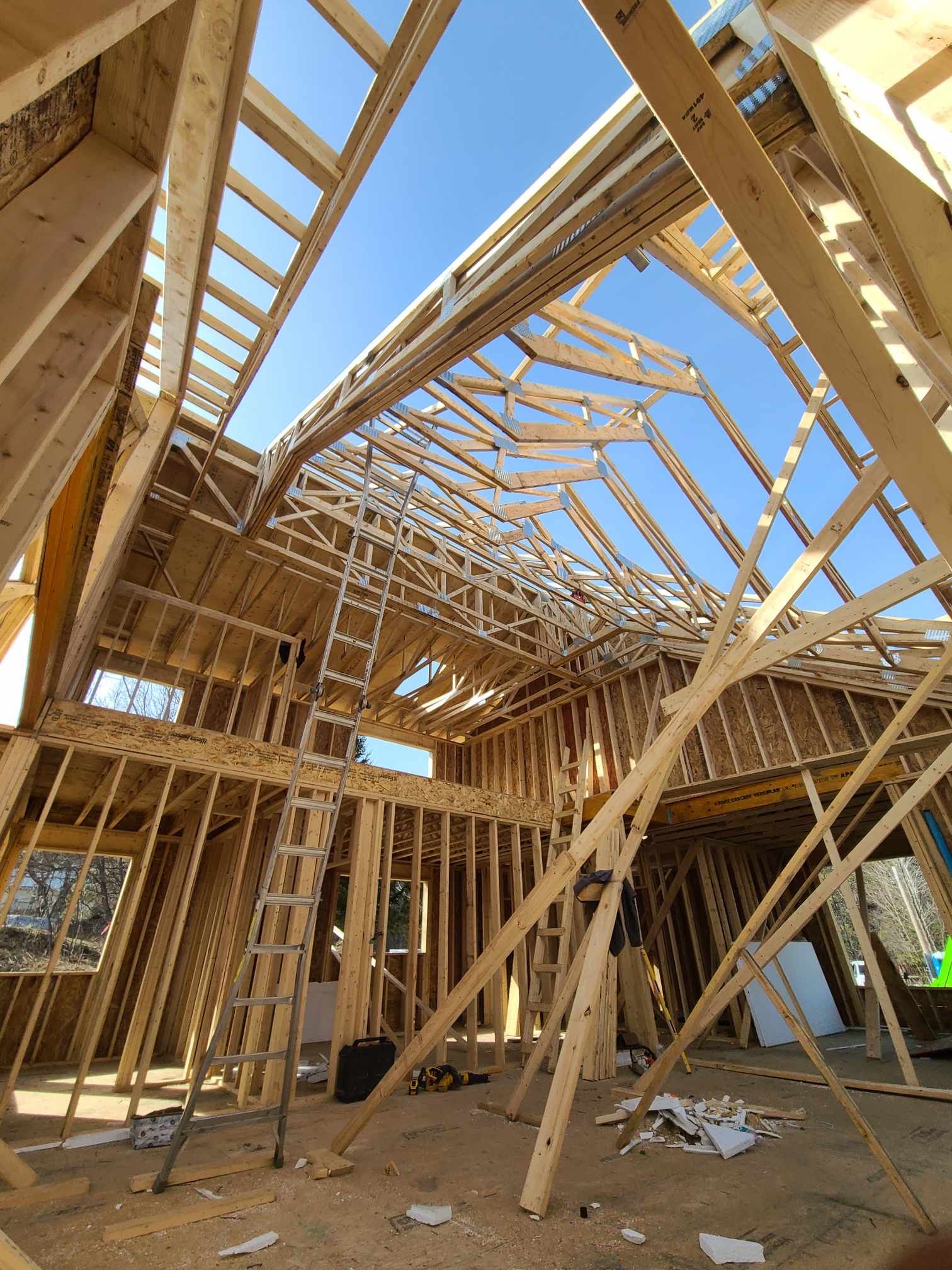Maison à ossature bois en construction, charpente apparente et ciel bleu au-dessus