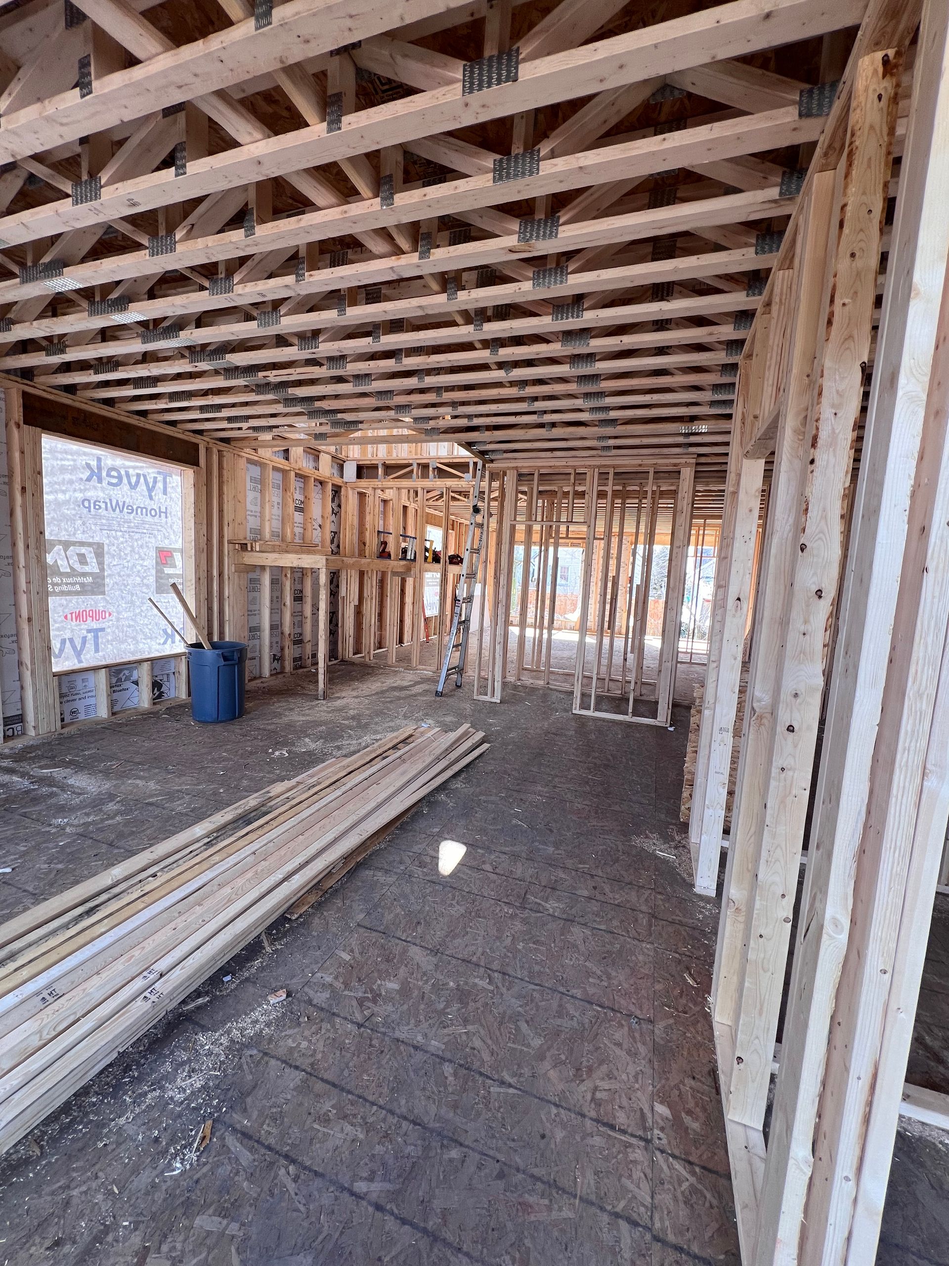 Intérieur d'une maison en construction avec charpente apparente, bois empilé et sol en terre battue