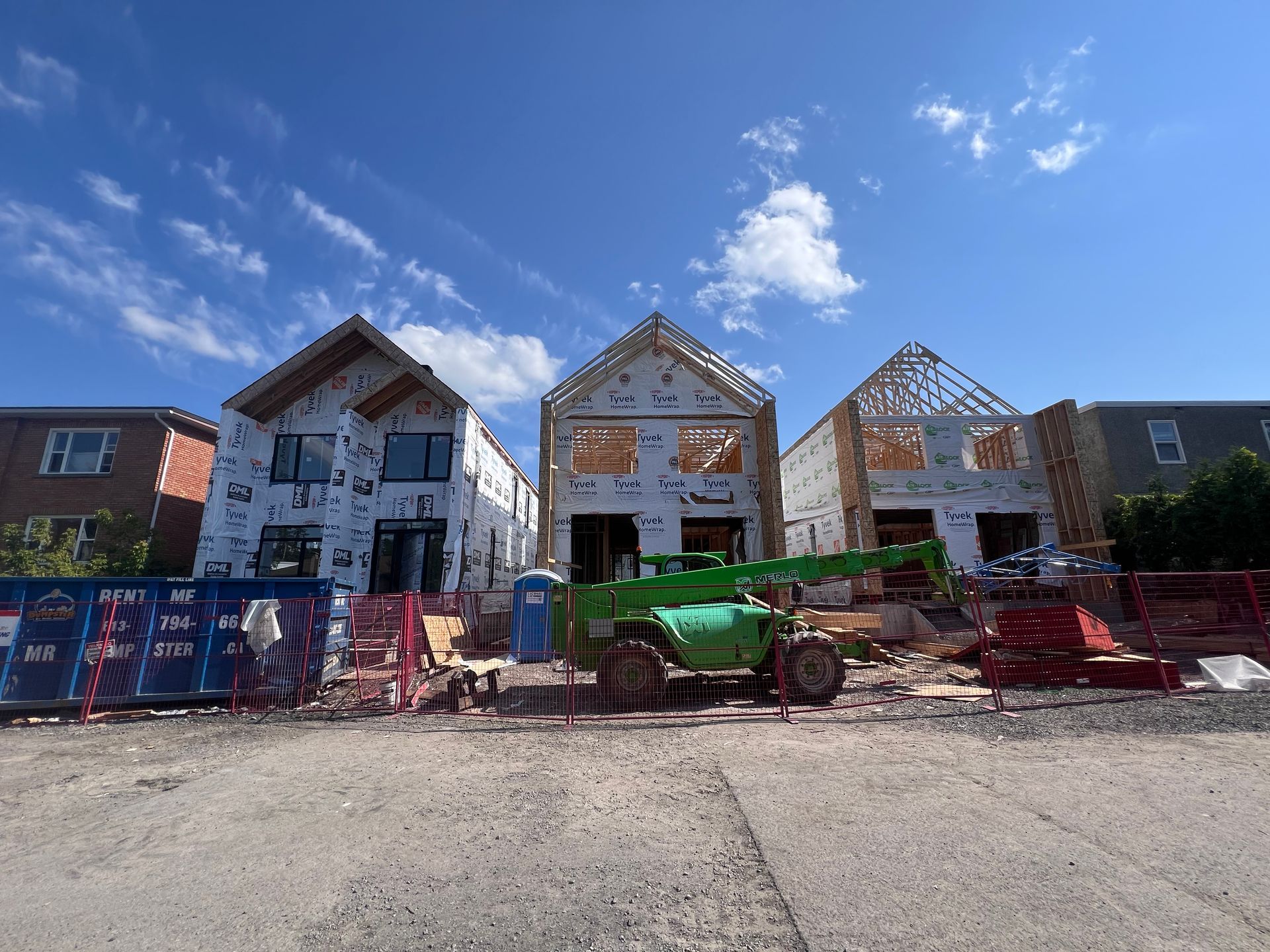 Des maisons en construction derrière des barrières et des engins de chantier par une journée ensoleillée