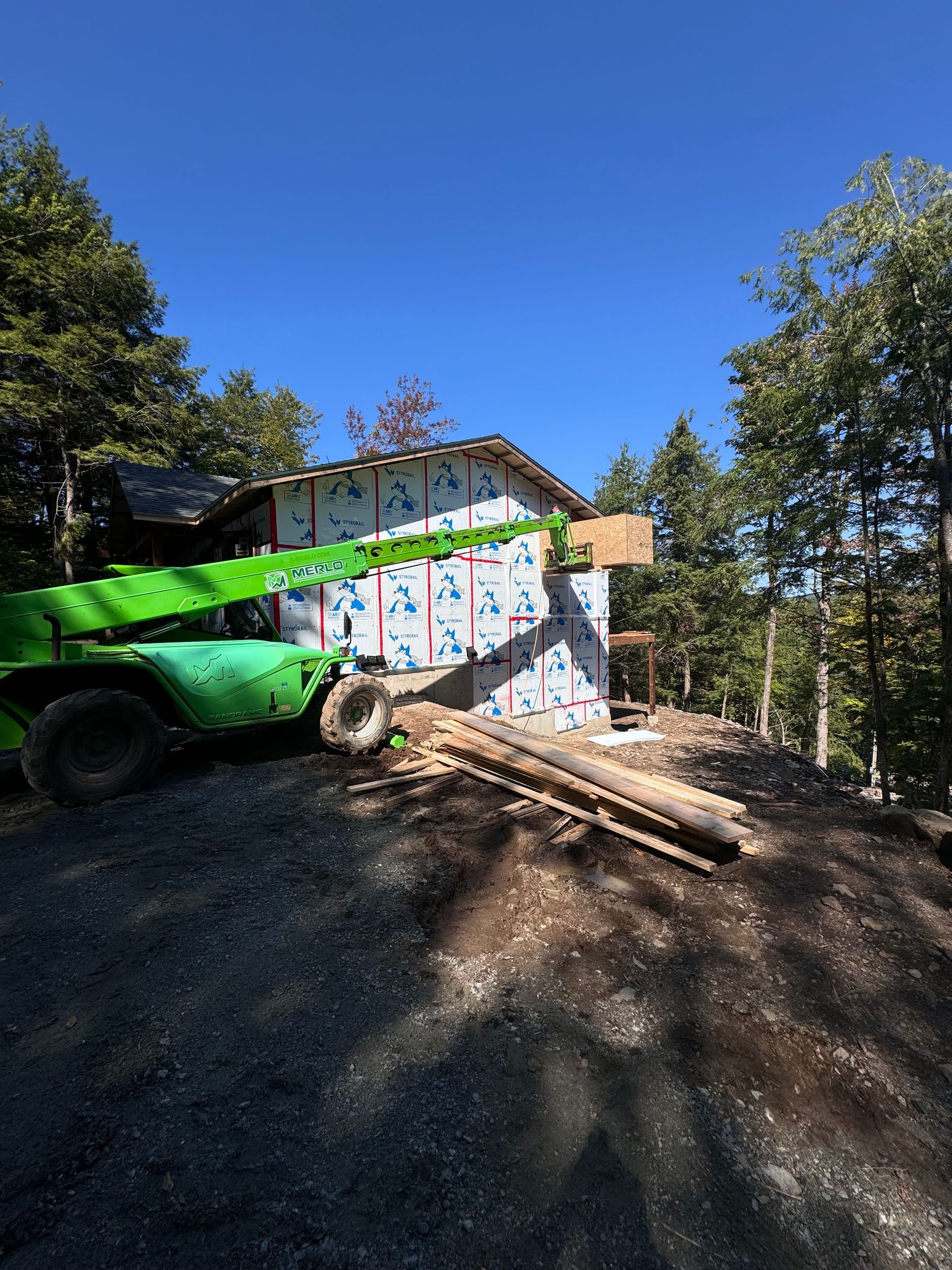 Véhicule de chantier vert à côté d'un bâtiment couvert de graffitis dans une zone boisée extérieure