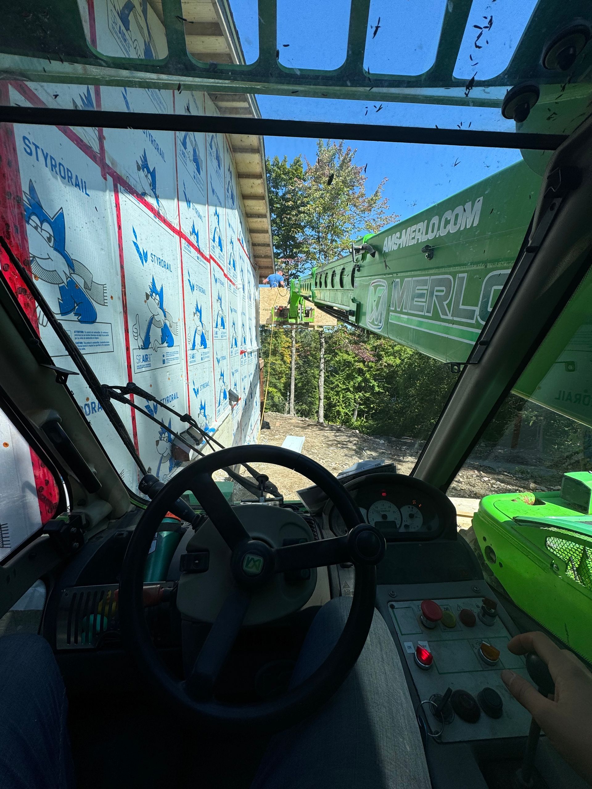 Dans la cabine du véhicule, le volant et les commandes font face à un passage étroit longeant des murs couverts de graffitis et de verdure.