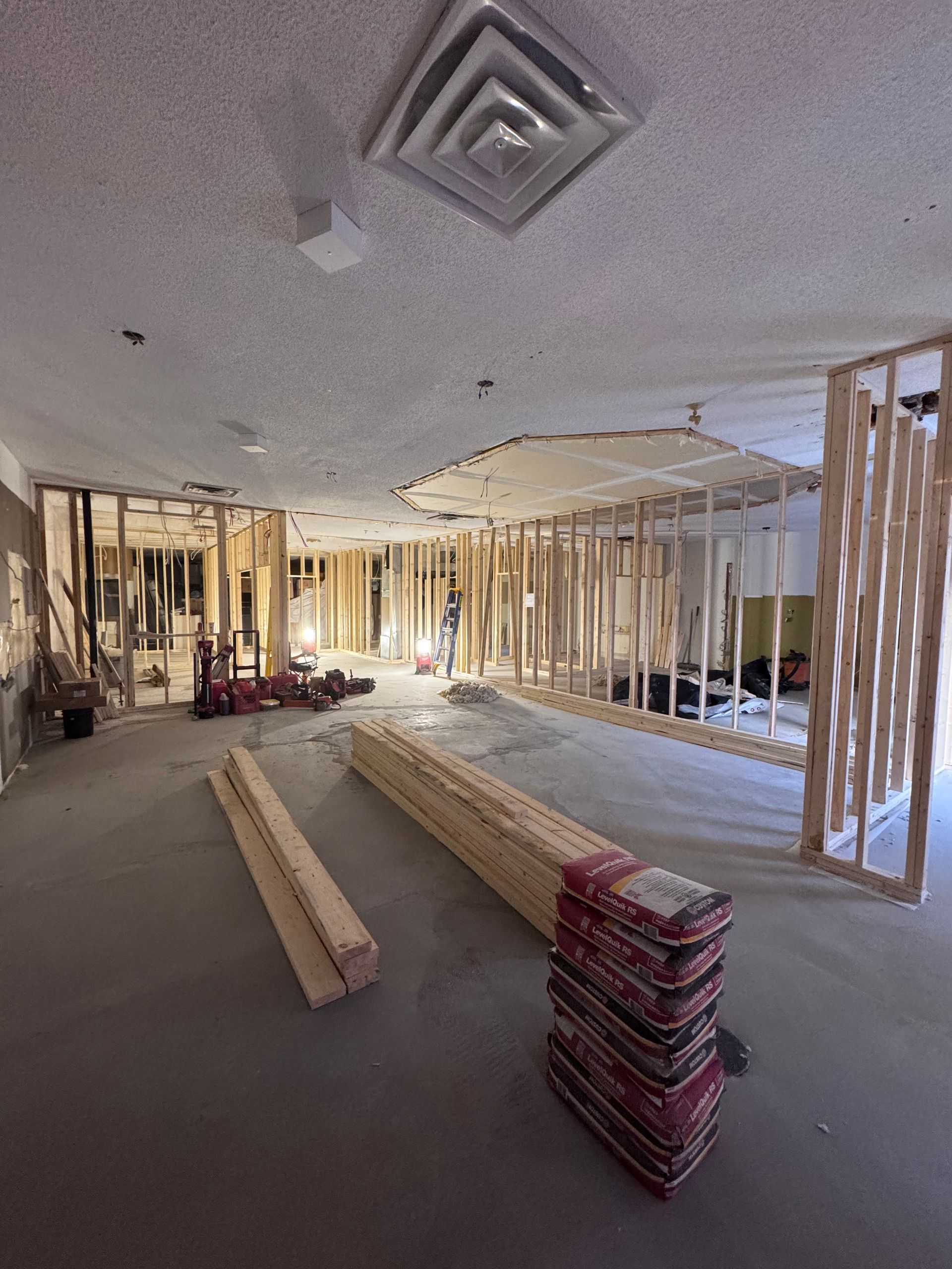 Intérieur en cours de construction avec ossature bois, isolation et piles de matériaux de construction sur un sol en béton.