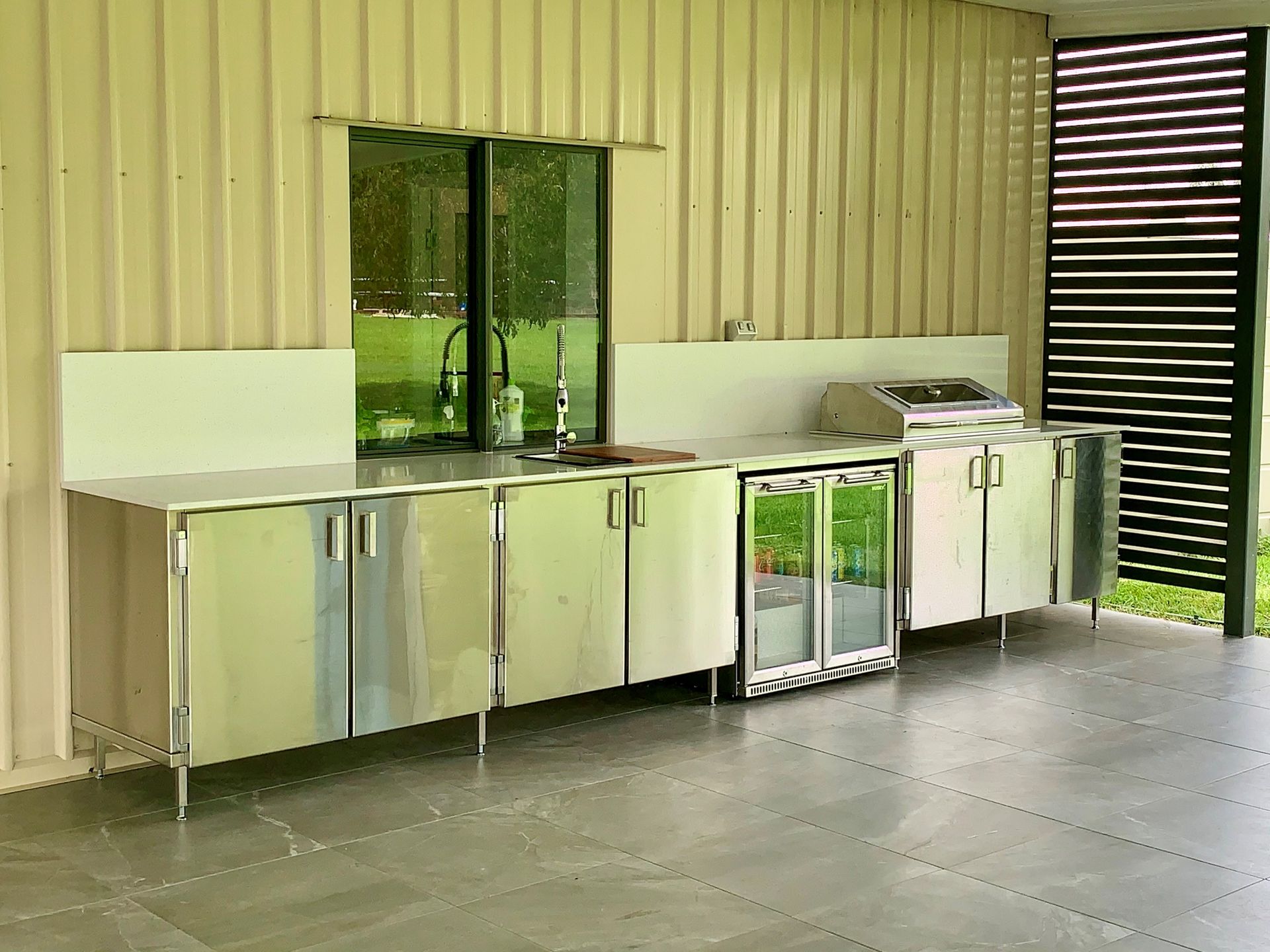 A Kitchen With Stainless Steel Cabinets And A Stone Wall — Townsville Stainless Steel in Garbutt, QLD