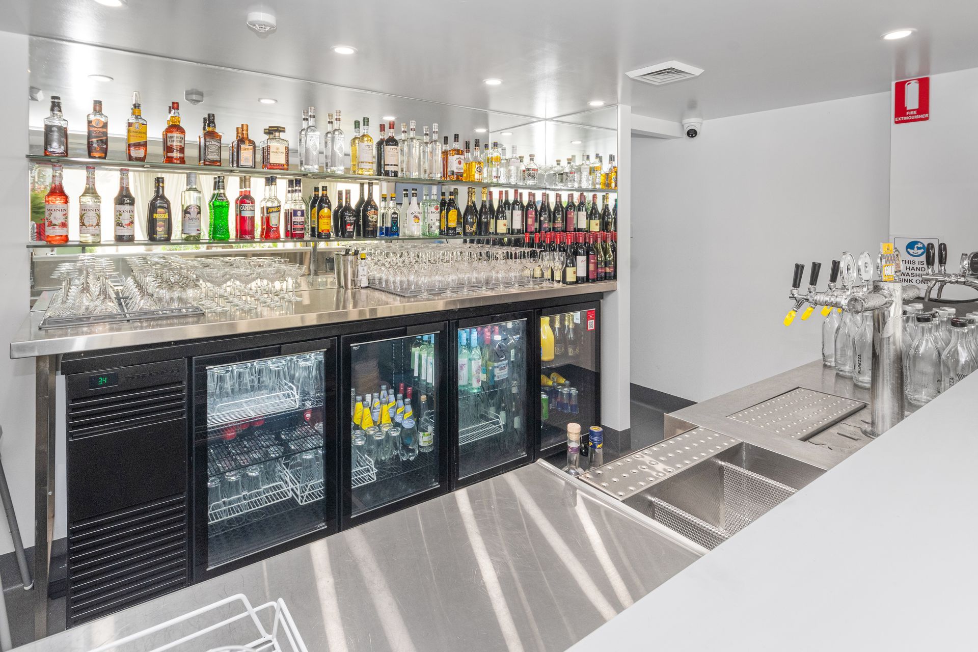 A Modern Bar With Stainless Steel Counters, Shelves of Liquor Bottles, and Coolers  — Townsville Stainless Steel in Garbutt, QLD