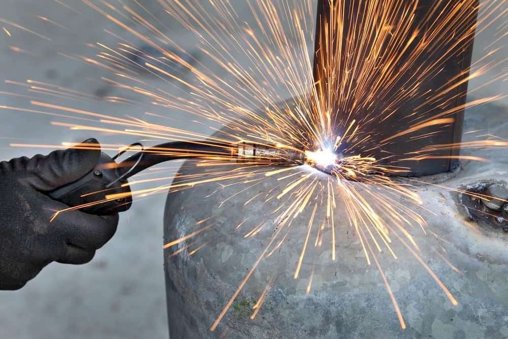 Welder Using Pliers, Sparks Flying From the Point of Contact — Townsville Stainless Steel in Atherton, QLD
