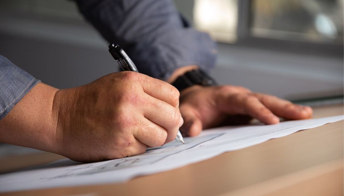 A Man Is Writing on A Piece of Paper with A Pen — Townsville Stainless Steel in Garbutt, QLD A Man Is Writing on A Piece of Paper with A Pen — Townsville Stainless Steel in Garbutt, QLD