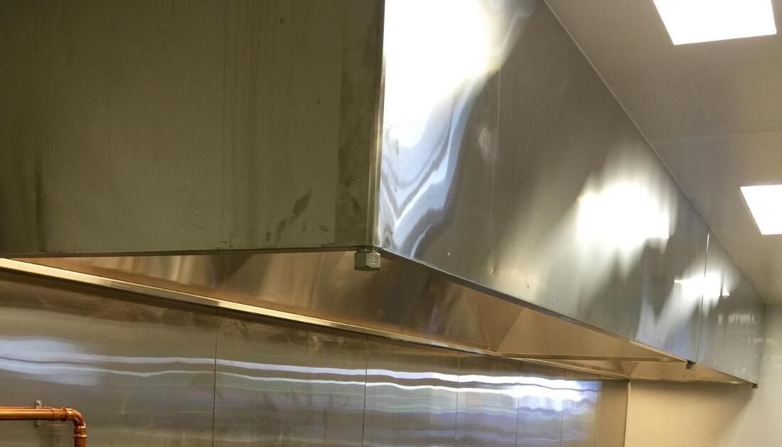 A Stainless Steel Hood Is Hanging from The Ceiling in A Kitchen  — Townsville Stainless Steel in Garbutt, QLD
