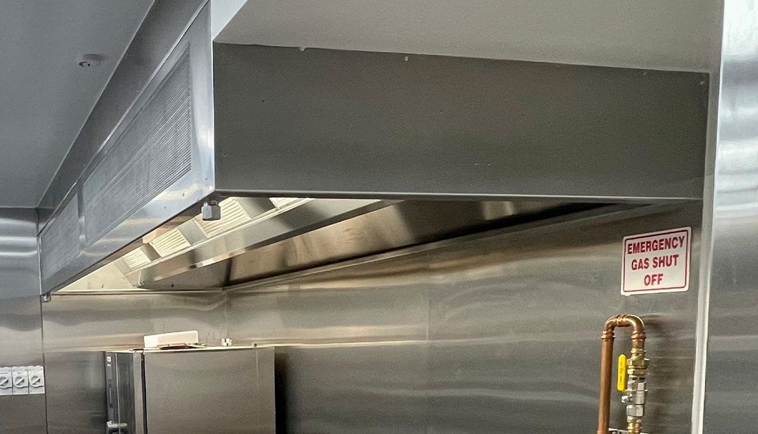 A Stainless Steel Hood Is Hanging from The Ceiling in A Kitchen  — Townsville Stainless Steel in Garbutt, QLD