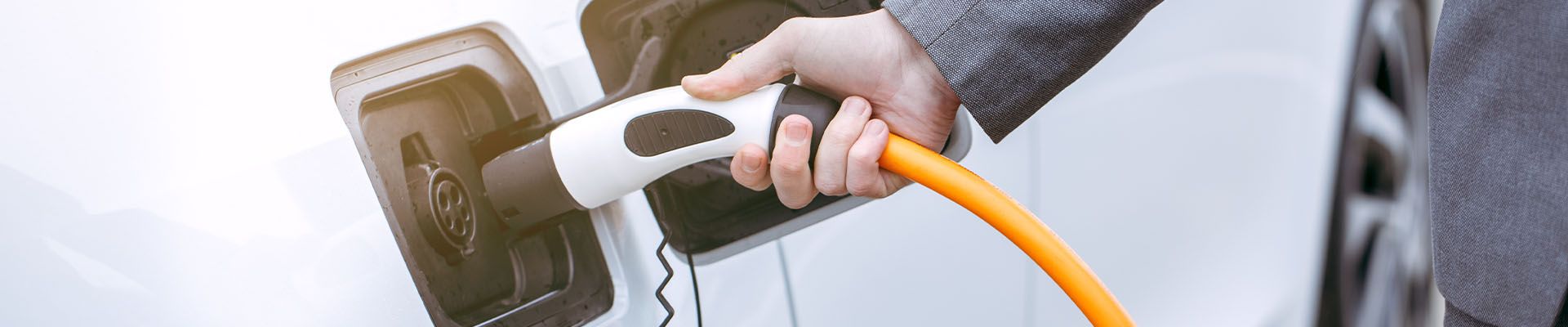 Stock image of a person plugging in an electric car.