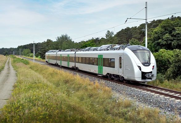 An electric train travels along a track towards the camera, through the British countryside.