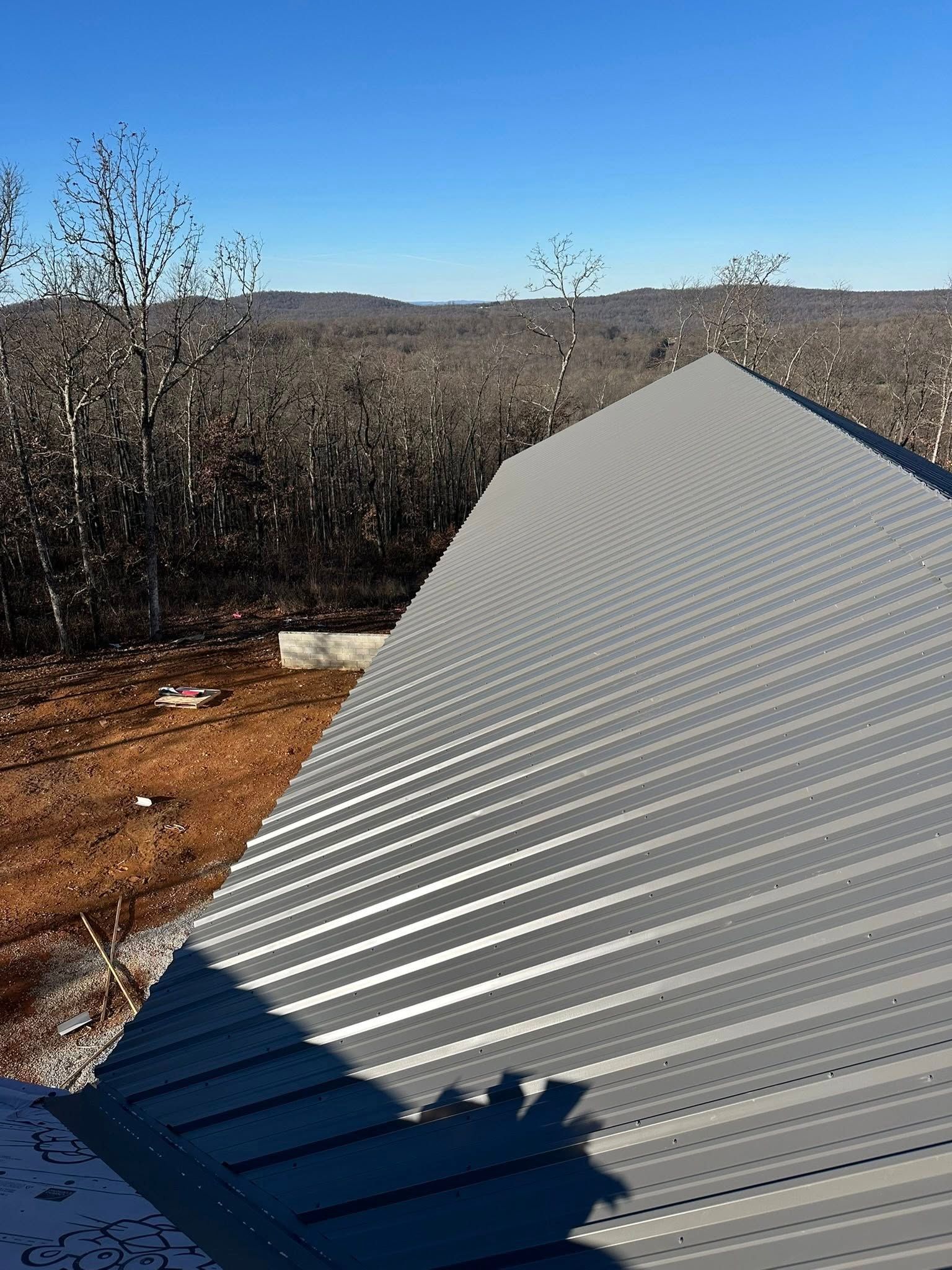 Corrugated metal roof extending into a dry, wooded landscape under clear daylight