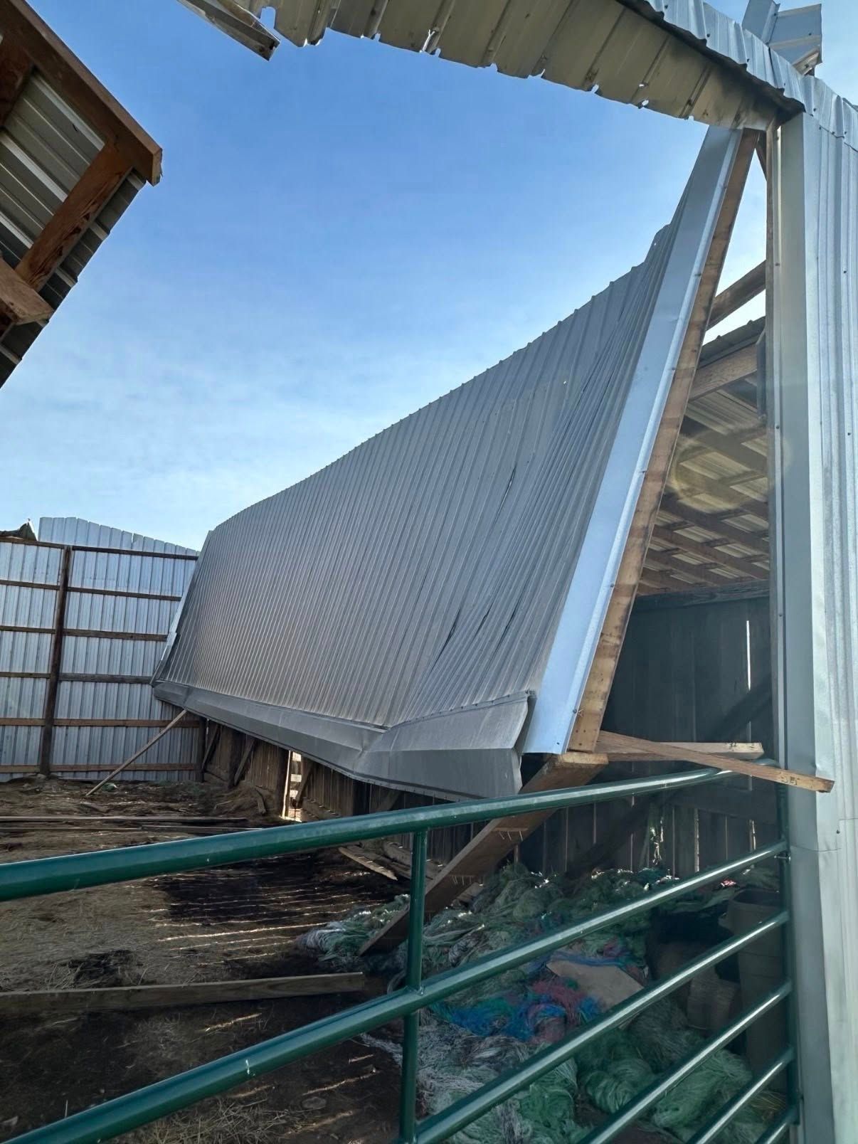 Collapsed tarp roof over a fenced outdoor area, with bent metal frame and debris.