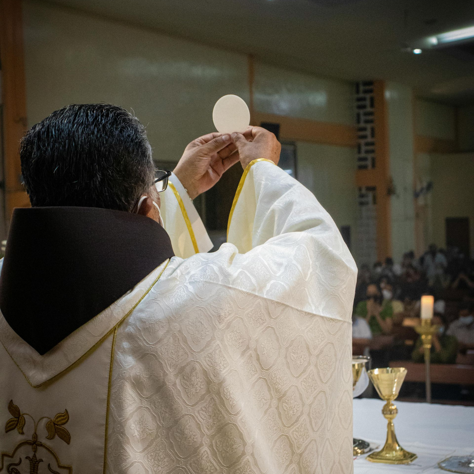 Priest in ornate vestments holds an intricate monstrance in a church. Priest in ornate vestments holds an intricate monstrance in a church.