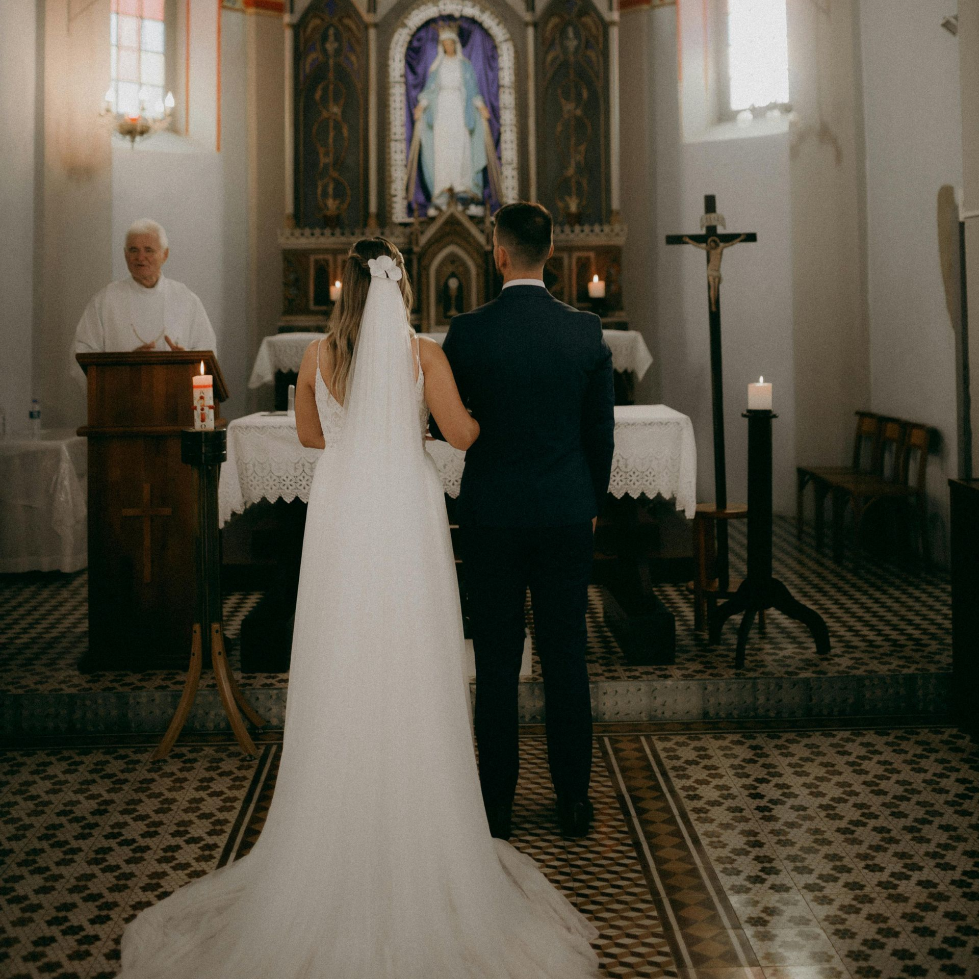 A bride and groom stand hand in hand at the altar in a church. A bride and groom stand hand in hand at the altar in a church.