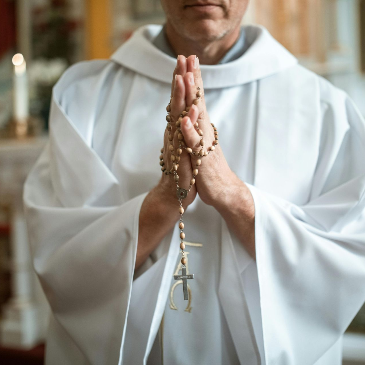 A man in a white robe stands at a wooden pulpit in a church, speaking into a microphone. A man in a white robe stands at a wooden pulpit in a church, speaking into a microphone.