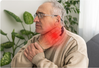 An elderly man is sitting on a couch with a sore throat.