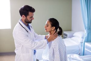 doctor-examining-patients-neck-in-hospital