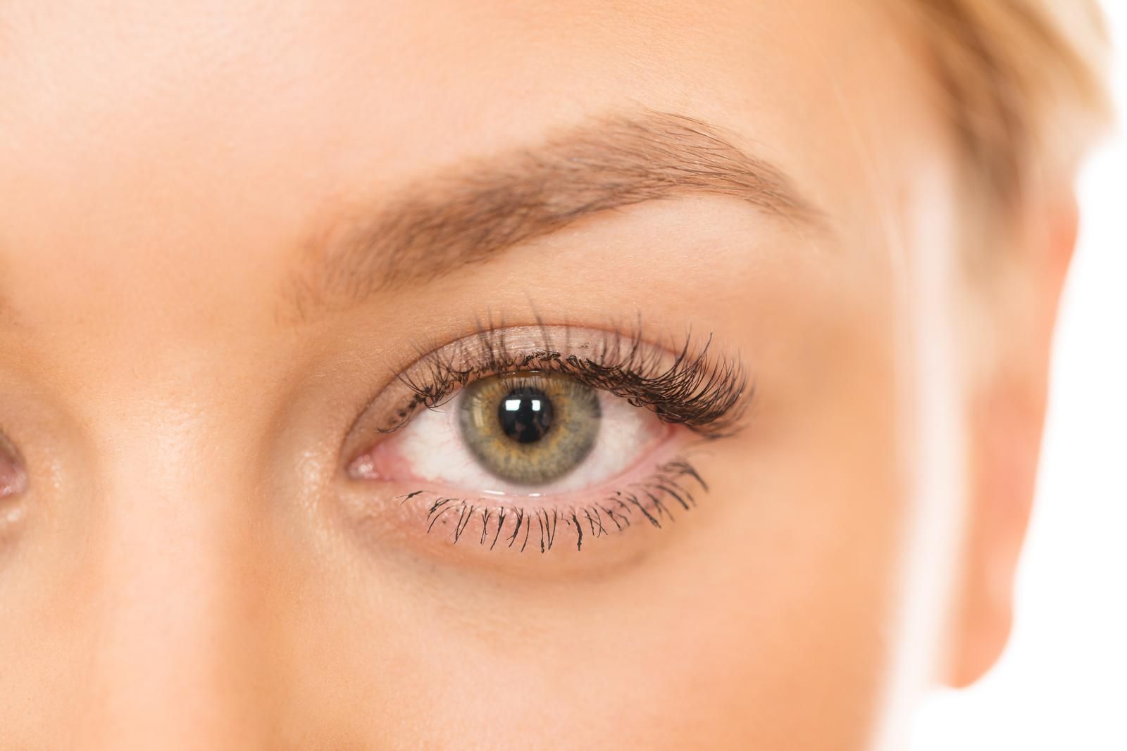 A close up of a woman 's green eye with long eyelashes.