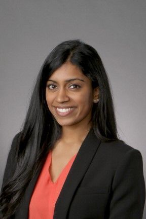 A woman in a black jacket and red shirt is smiling for the camera.