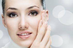 A woman is touching her face with her hand and smiling.