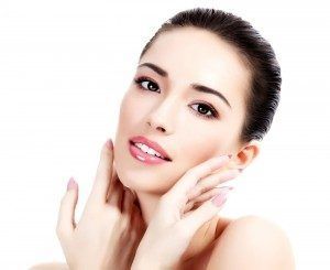 A woman is touching her face with her hands and smiling.