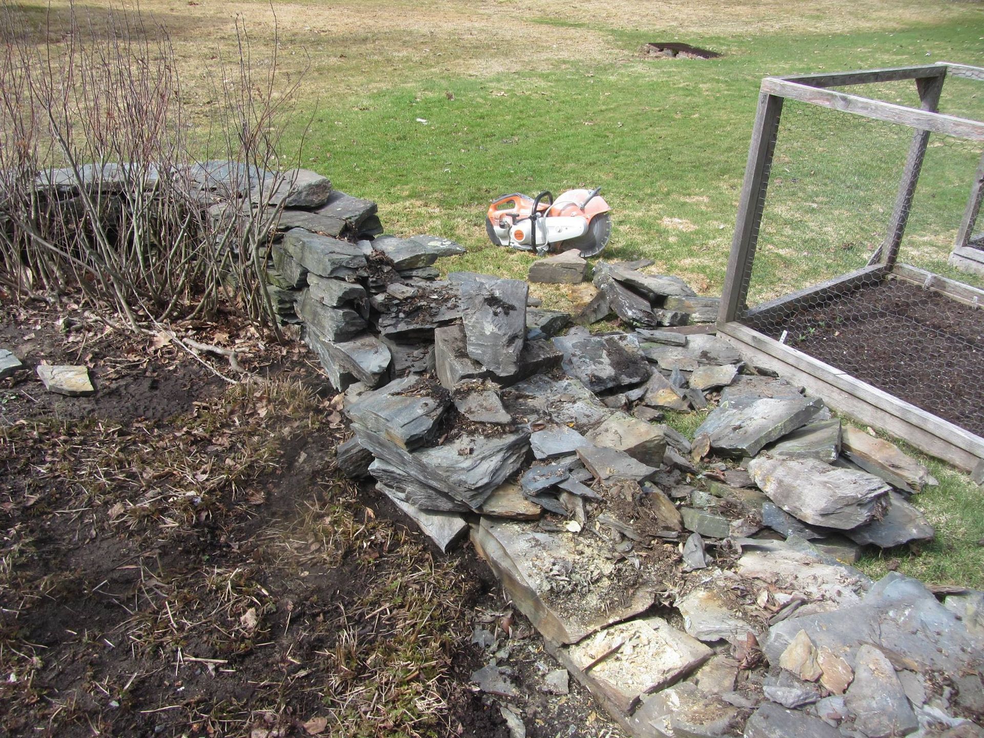 Rock garden with stacked stones beside a grassy yard and metal railing.