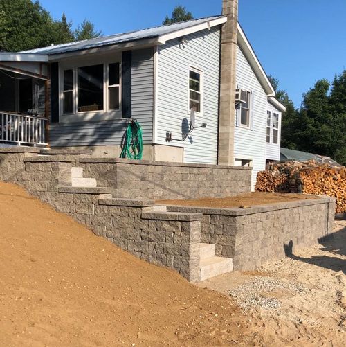 House with stone retaining walls on a sloped yard under construction