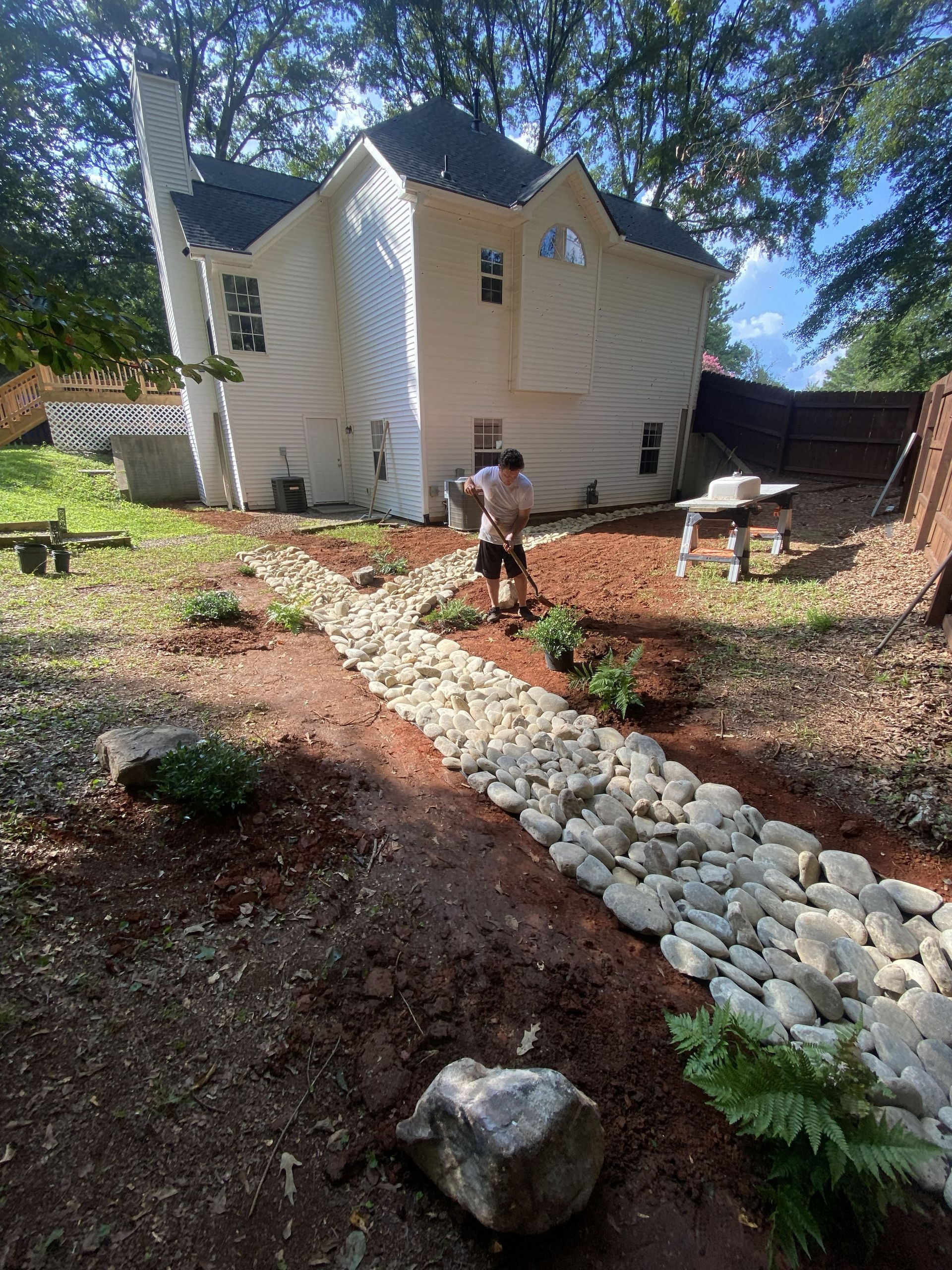 White house with a stone path and landscaping, with a person standing in the yard.