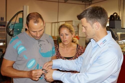 Zwei Männer und eine Frau schauen sich etwas in einer Fabrik an