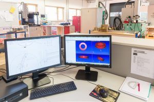 Zwei Computermonitore stehen auf einem Schreibtisch in einem Labor.