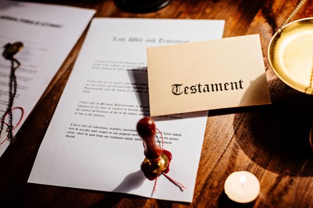 Busta del testamento sopra documenti legali su un tavolo di legno accanto a una candela