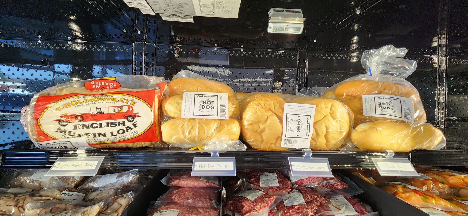 A bunch of bread is sitting on a shelf in a refrigerator.