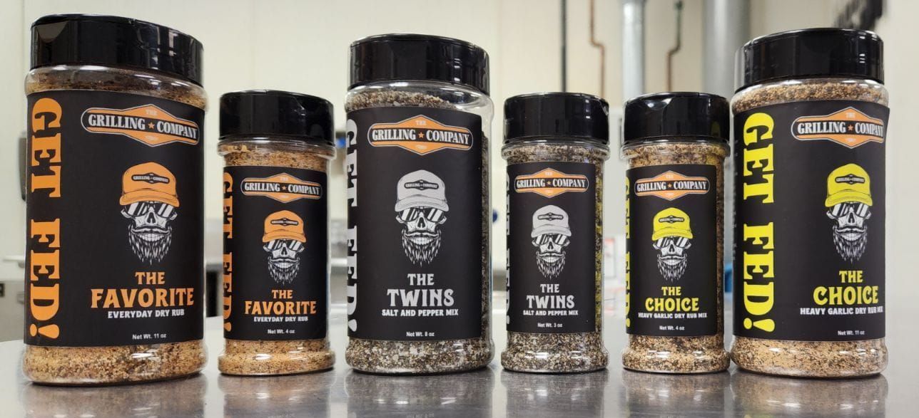 A row of bottles of seasoning are lined up on a counter.