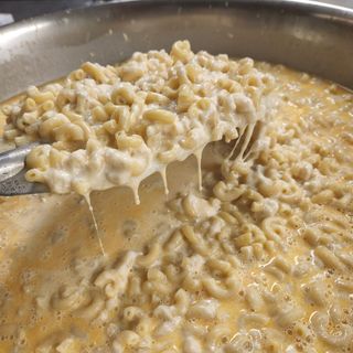 Macaroni and cheese is being scooped out of a pot with a fork.