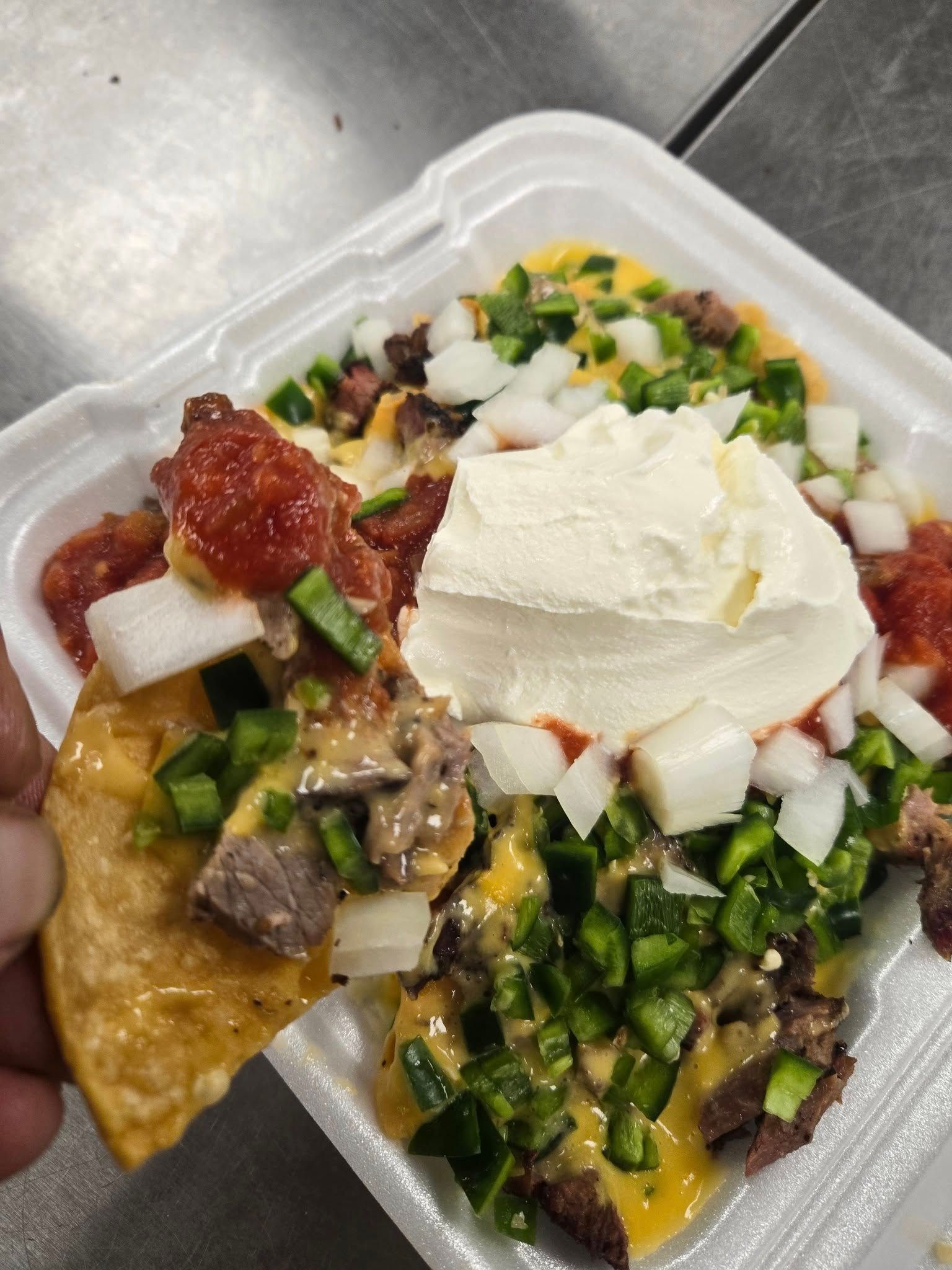 A person is taking a tortilla chip out of a styrofoam container