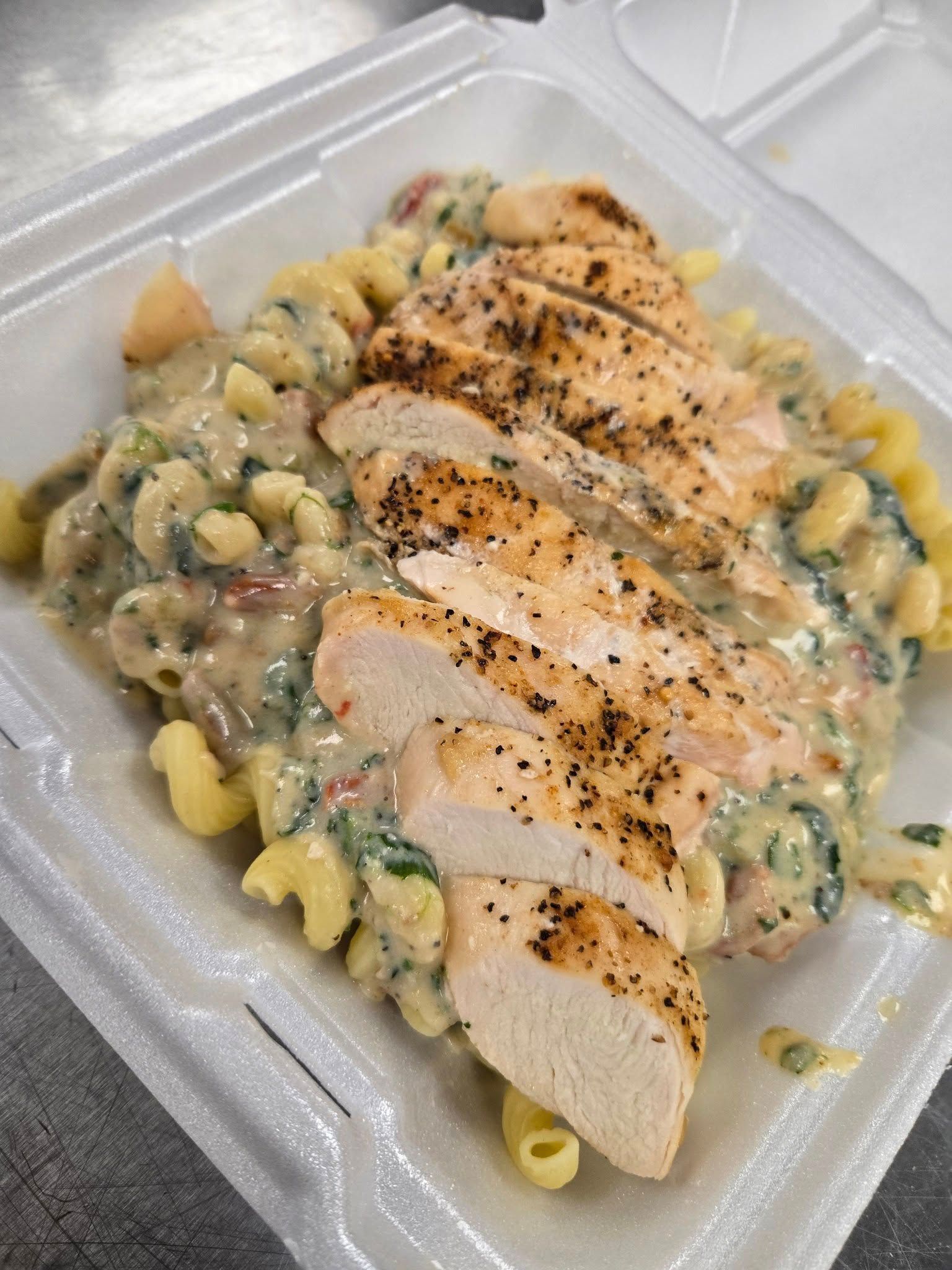 A styrofoam container filled with macaroni and cheese and chicken.