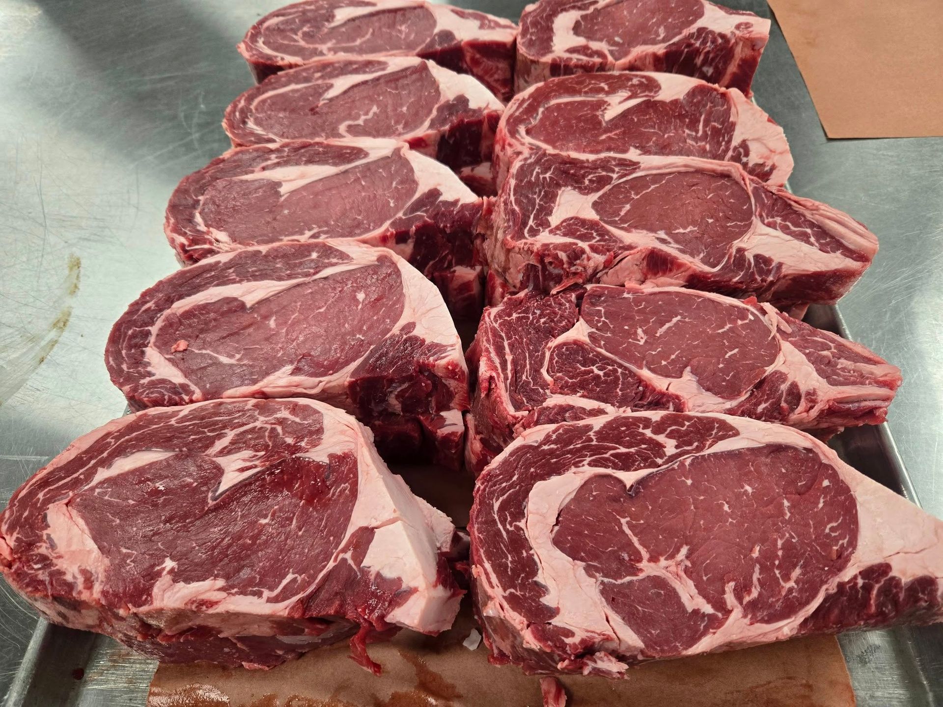 A bunch of raw steaks are sitting on a tray on a table.