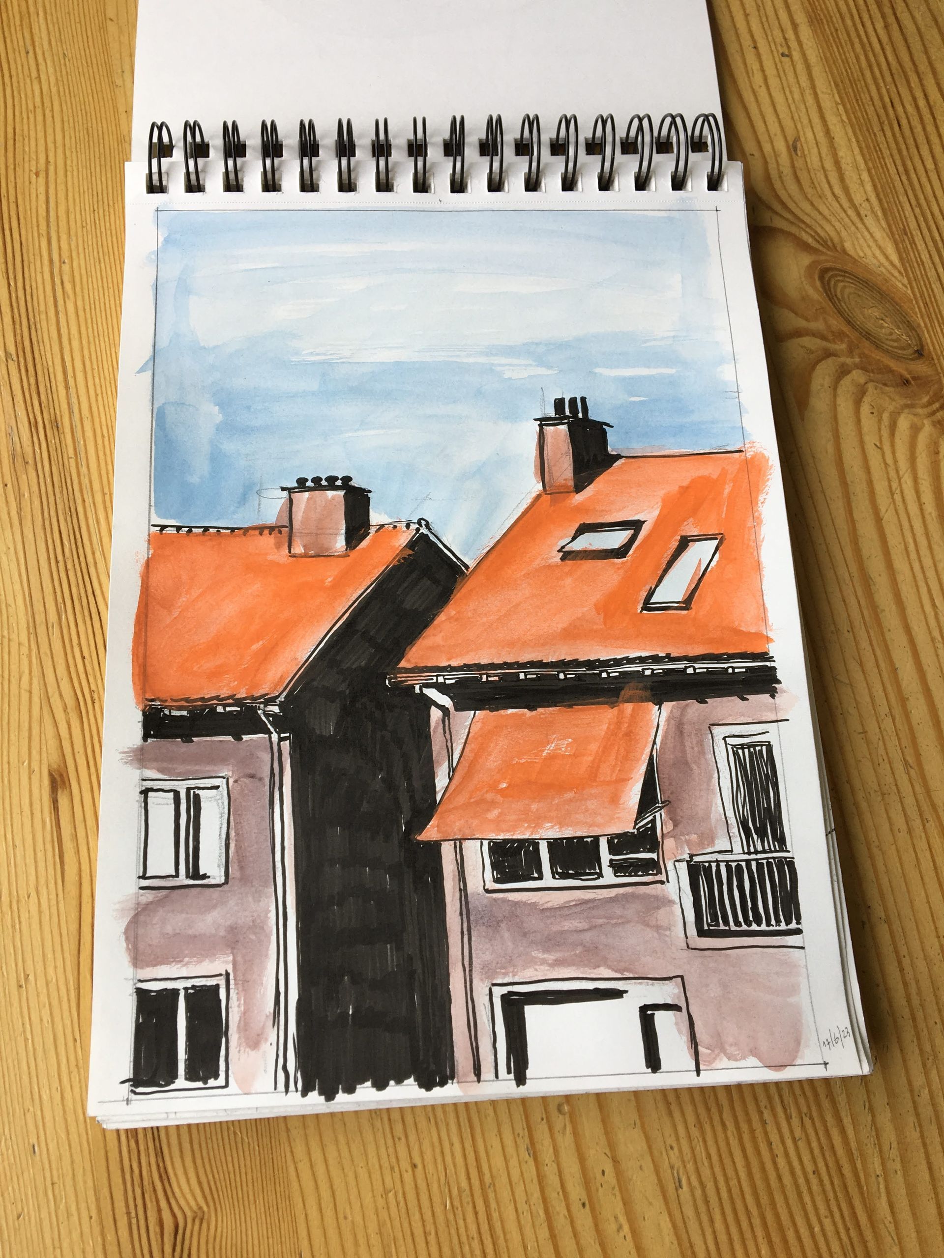 Schets van twee gebouwen met oranje daken, zwarte schaduwen en een blauwe lucht in een schetsboek op hout.