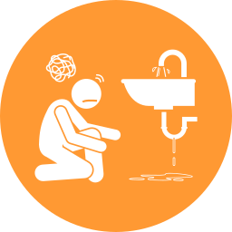 A man is kneeling down next to a sink with water coming out of it.