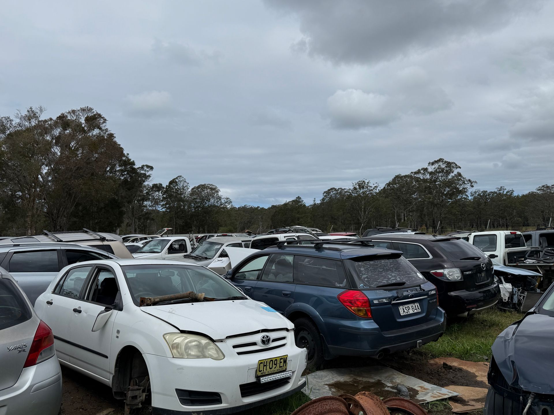 A White Boat Is Sitting On A Trailer In The Grass — Old Bar Wreckers In Glenthorne, NSW