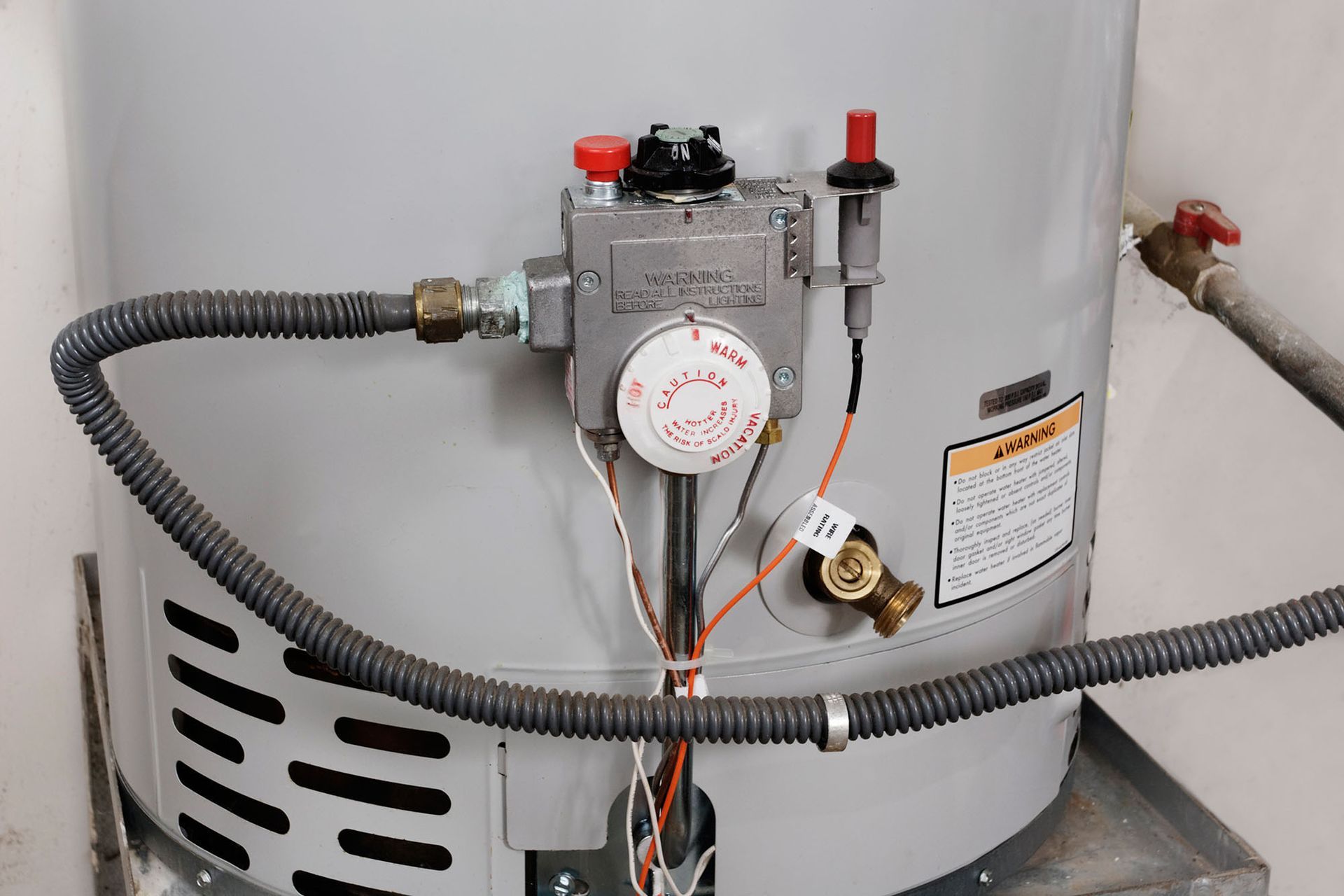 White water heater with gas control valve and hoses in a utility area
