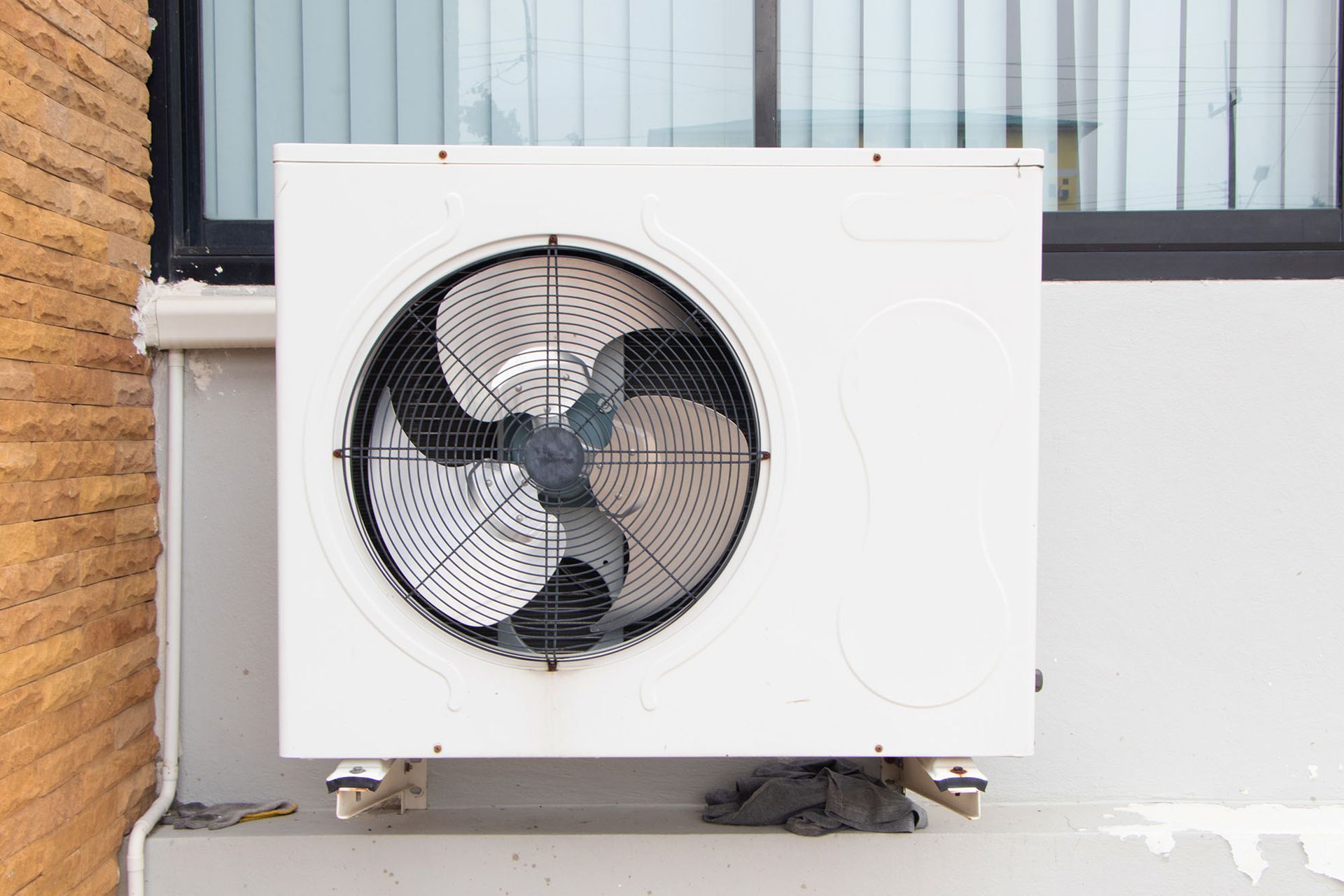 White outdoor air conditioning unit with a large fan mounted on an exterior wall.