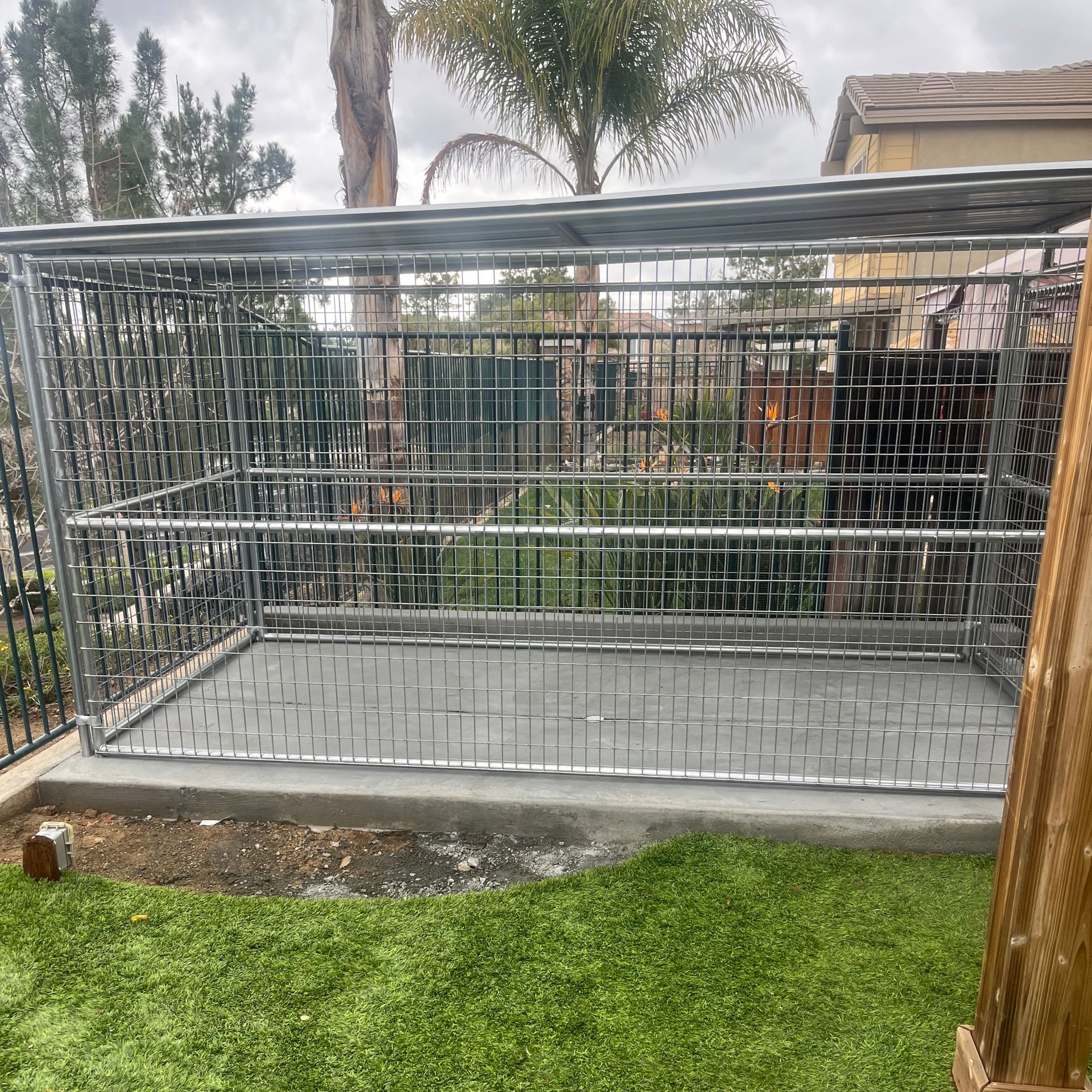 A large dog cage is sitting on top of a lush green lawn.