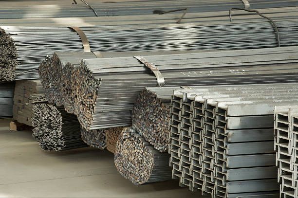 Stacked galvanized steel channels and metal bars stored in warehouse for construction use projects.