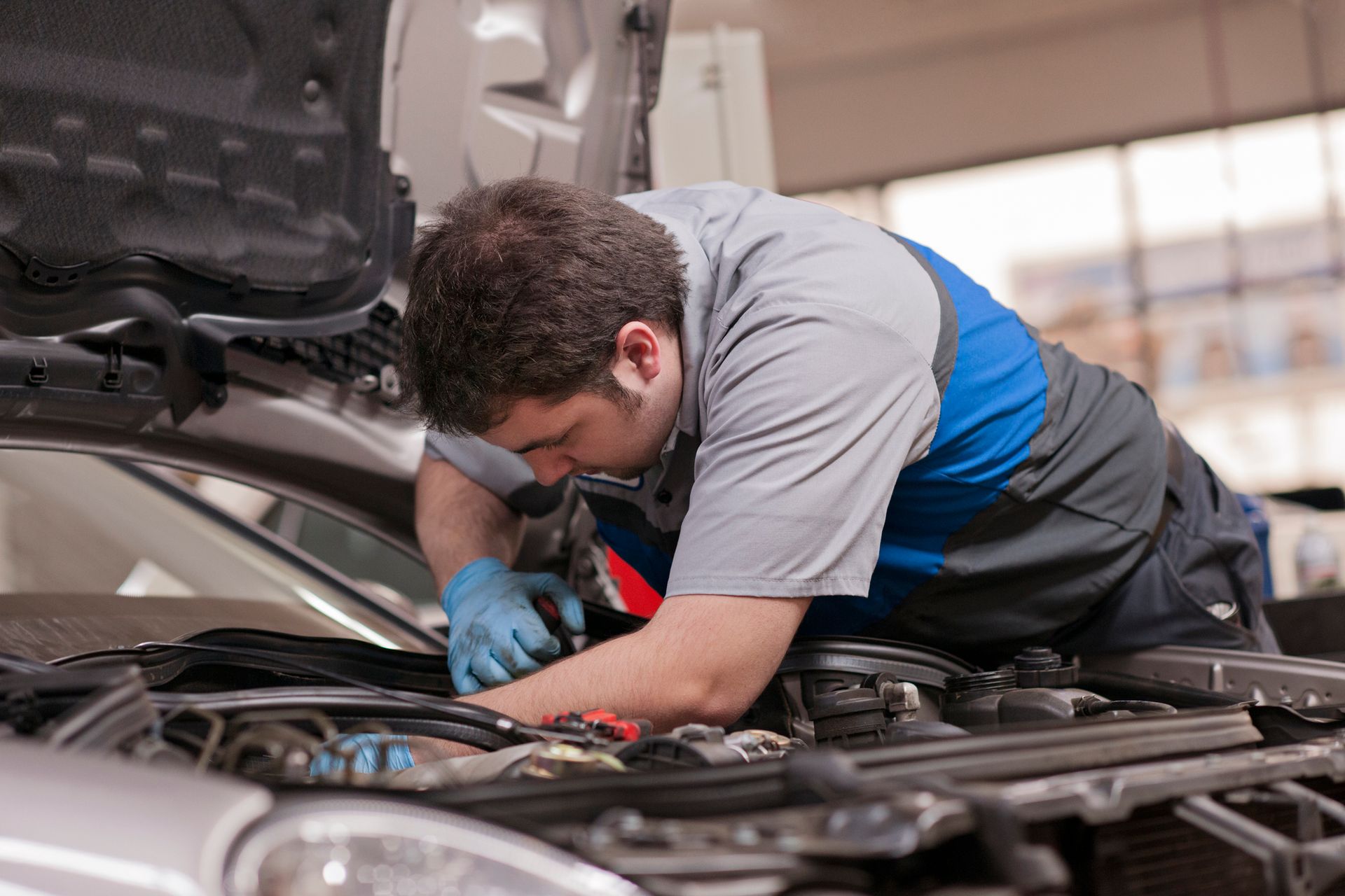 A mechanic inspecting a car's engine in a garage, showcasing Mercedes-Benz auto repair skills.
