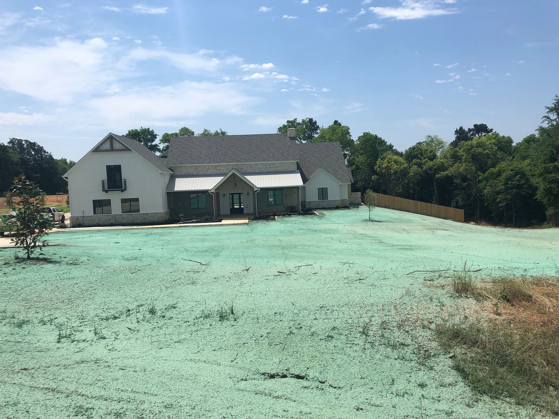 Newly built house with white siding and a green-covered lawn, sunny day.